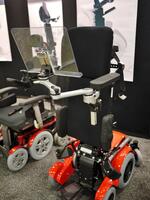 As you can see, the mount and tray are in the same position relative to the person in a standing position. This is the benefit of attaching to a standing wheelchair's armrest where possible. The armrests on a standing wheelchair are typically more stable.
